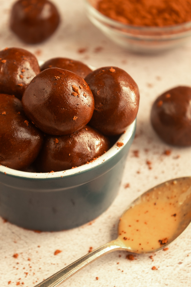 Angled shot of Chocolate Peanut butter protein balls with sprinkle of cocoa powder.