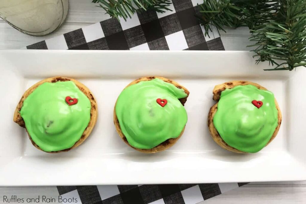 Overhead shot of 3 grinch cinnamon rolls on rectangular plate.