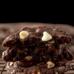 Best white chip chocolate cookies on wire rack stacked and broken in half showing the centers.