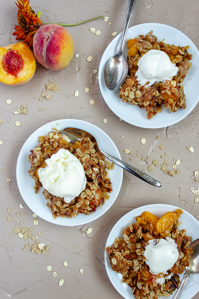 Easy peach crisp with oats on 3 plates with spoons overhead shots.