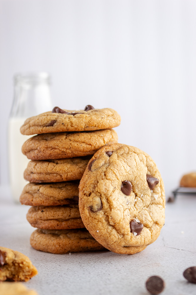 Straight on shot of Brown Butter chocolate chip cookies stacked on top of eachother wiht one in front.